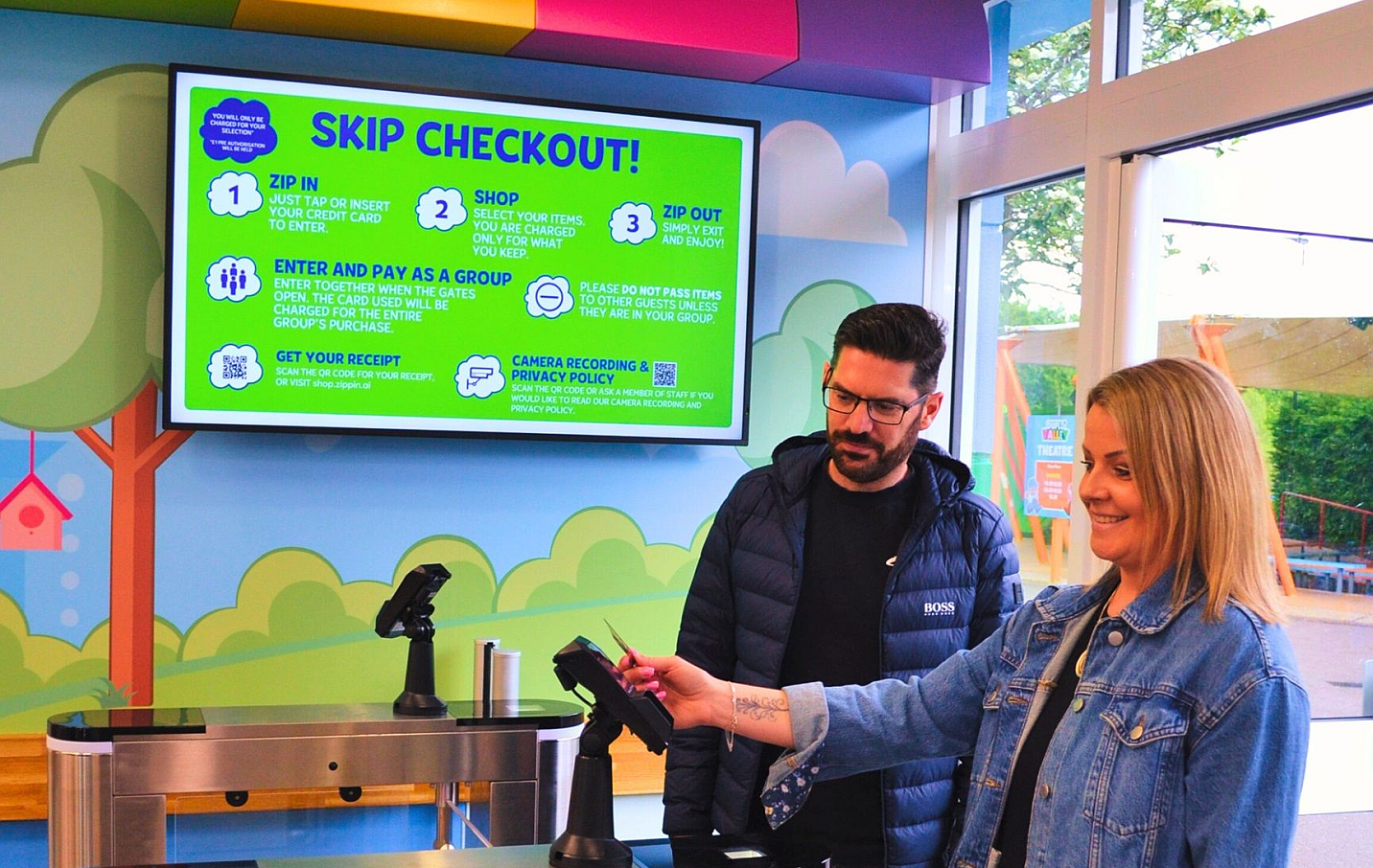Two people using the skip checkout kiosk at a LegoLand shop.